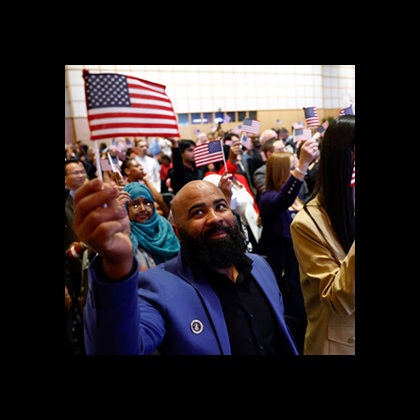 A group of diverse people hold small American flags at an event.