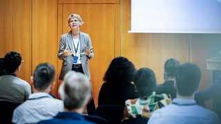 A presentation being given by a businesswoman to a group of participants at a business conference.